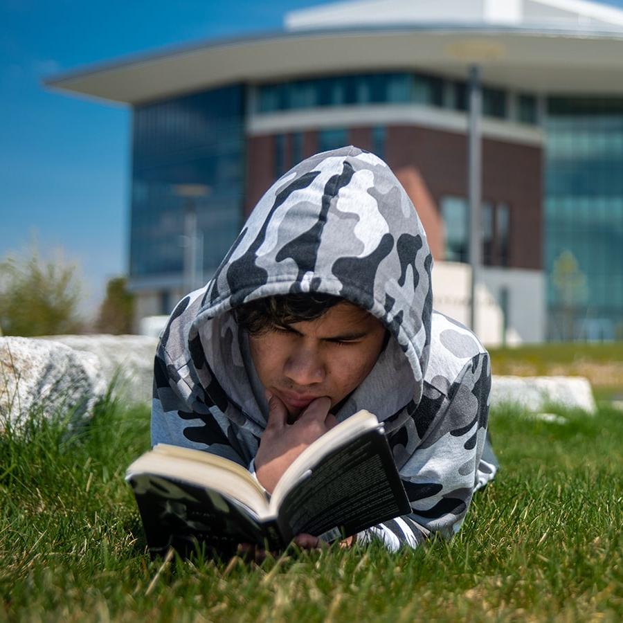 躺在校园草坪上看书的学生